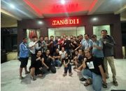 Sejumlah pria berpose bersama di depan gedung bertuliskan TANG II pada malam hari sambil mengangkat tangan dengan gestur kepalan.