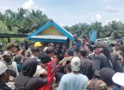 Kerumunan pekerja dan petugas pengamanan berkumpul di depan bangunan barak di area perkebunan kelapa sawit Rokan Hulu.