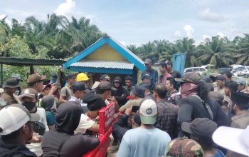 Kerumunan pekerja dan petugas pengamanan berkumpul di depan bangunan barak di area perkebunan kelapa sawit Rokan Hulu.