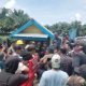 Kerumunan pekerja dan petugas pengamanan berkumpul di depan bangunan barak di area perkebunan kelapa sawit Rokan Hulu.