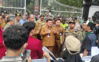 Pejabat pemerintah daerah memberikan pernyataan kepada warga dan aparat di depan gerbang kantor pemerintahan saat berlangsungnya pertemuan di area luar gedung.