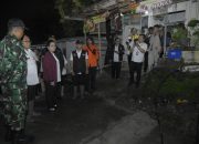 Sejumlah pejabat daerah bersama petugas TNI dan tim penanganan bencana meninjau lokasi terdampak pergerakan tanah di kawasan permukiman pada malam hari.