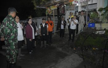 Sejumlah pejabat daerah bersama petugas TNI dan tim penanganan bencana meninjau lokasi terdampak pergerakan tanah di kawasan permukiman pada malam hari.