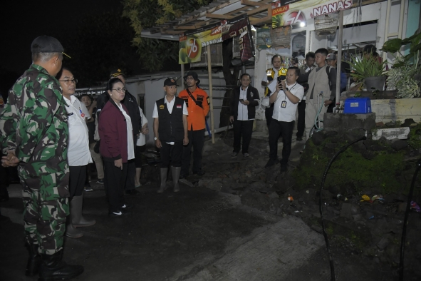 Sejumlah pejabat daerah bersama petugas TNI dan tim penanganan bencana meninjau lokasi terdampak pergerakan tanah di kawasan permukiman pada malam hari.