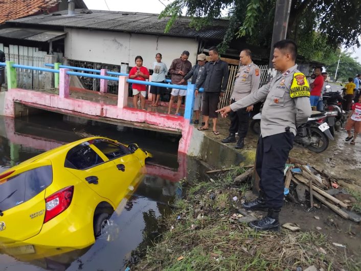 Petugas kepolisian dan warga melihat kondisi mobil yang terperosok ke Kali Apor di wilayah Rengasdengklok, Karawang, setelah diduga terlibat kecelakaan lalu lintas, Sabtu (31/1/2026).