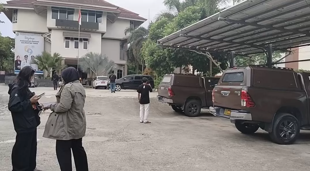 Dua kendaraan milik penyidik Kejaksaan Tinggi Kalimantan Timur (Kejati Kaltim) terlihat terparkir di halaman Kantor Dinas ESDM Kaltim saat proses penggeledahan berlangsung, Senin sore (16/3/2026).